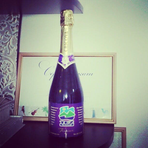An archive photograph of a souvenir bottle with TEZ Tour branding and a certificate on a shelf.