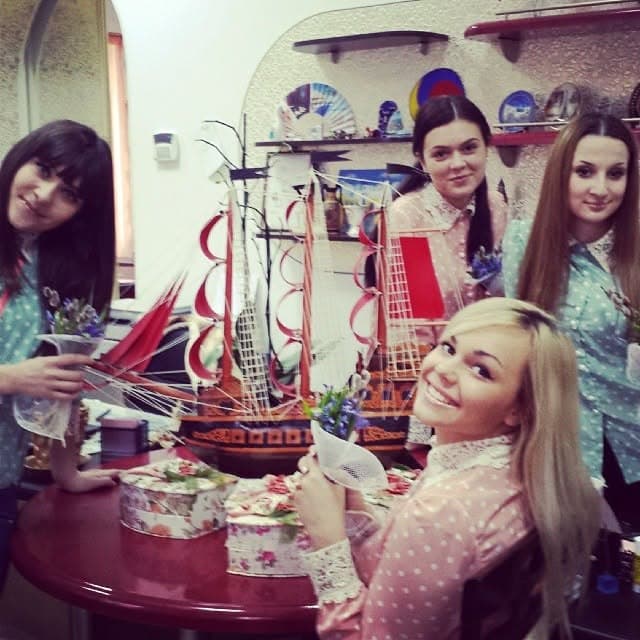 The team in the office beside a model sailing ship and flowers.